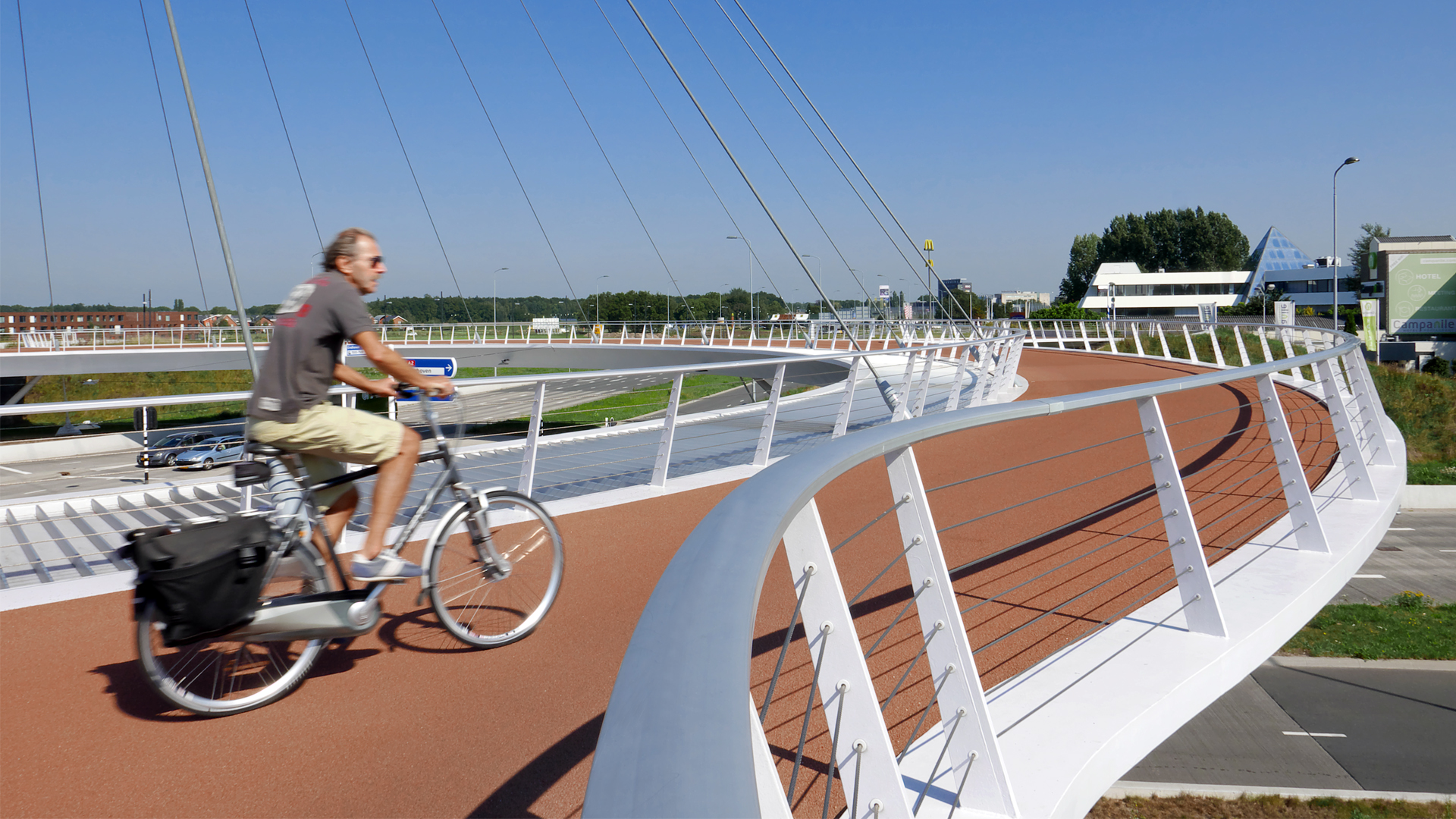 fietser op hovenring eindhoven, moderne pyloonbrug over de snelweg, fietsbrug ontwerp door ipv Delft