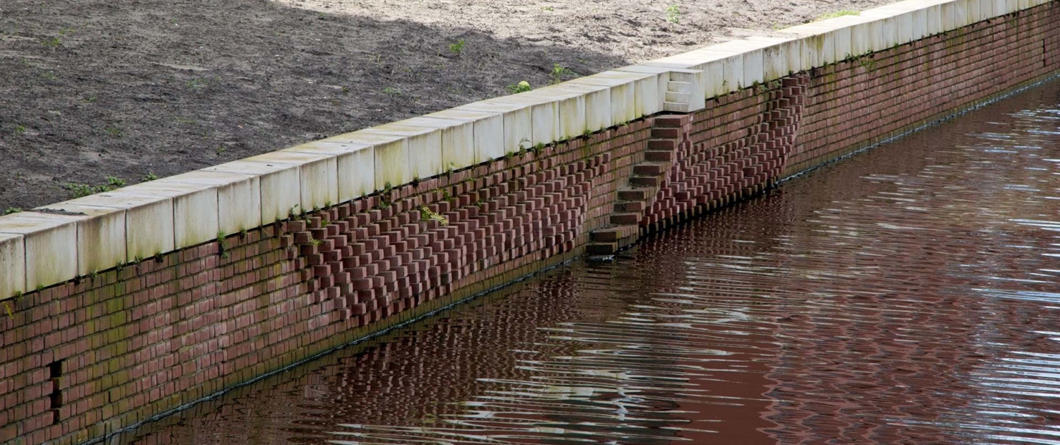 natuurinclusieve gemetselde kademuur met eendentrap, uitstekende stenen en plantenstekjes tussen voegen